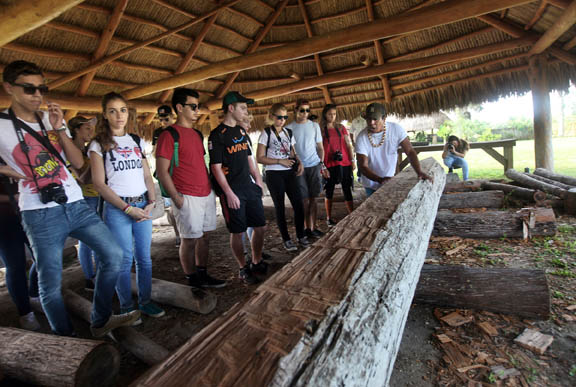 Big Cypress Culture Department representative Victor Billie, right, shows Italian foreign exchange students and teens from Archbishop McCarthy High School a Seminole canoe in the making Sept. 3 during a tour of Billie Swamp Safari on the Big Cypress Reservation. Seminole Tribe members John Osceola, 16, who is a junior at McCarthy, and John’s father, Gem Osceola, helped organize the excursion. 