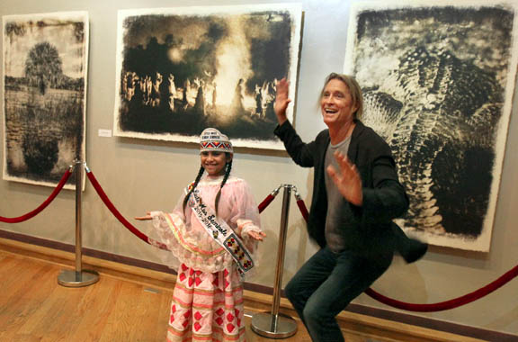 Little Miss Florida Seminole Victoria Bernard and photographer Russell James are happy to pose in front of James’ ‘Seminole Spirit’ photographs Sept. 25 at Ah-Tah-Thi-Ki Museum on the Big Cypress Reservation.