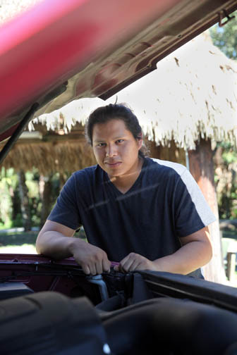 Reese Bert Jr. checks under the hood of an SUV at his mother’s home on Brighton Reservation. Bert graduated from Universal Technical Institute in Orlando on Sept. 4.