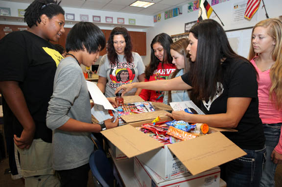 Students of Traci Mendez’s eighth-grade class at Pemayetv Emahakv Charter School examine boxes Nov. 13 that will be sent to troops overseas. Instructional coach Stephanie Tedders, at right, shows students and Mendez, in center, what has been packed in the boxes. 