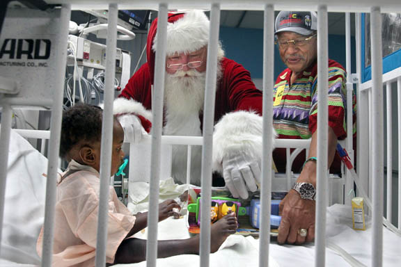 President Mitchell Cypress and Santa Claus deliver a toy to a baby in the intensive care unit Dec. 8 at Joe DiMaggio Children’s Hospital in Hollywood. President Cypress hosted a three-day toy drive prior to the delivery.