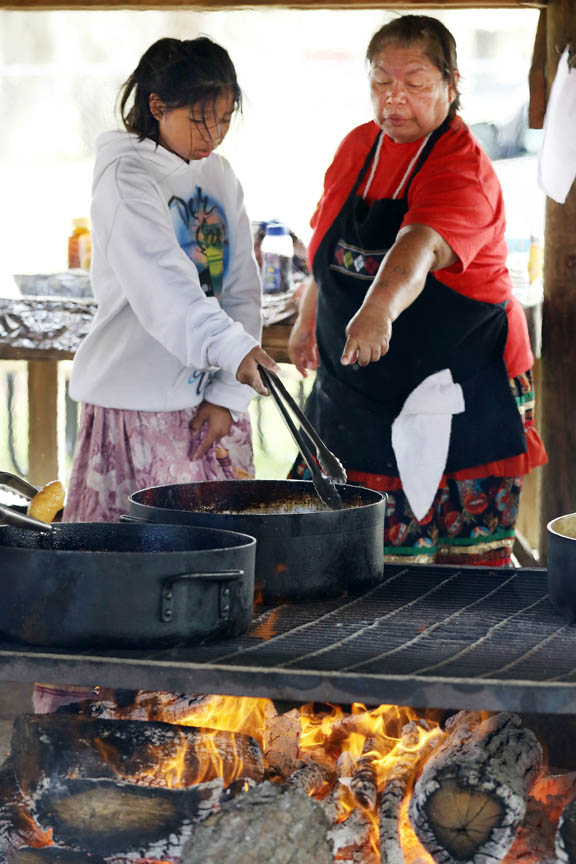 Fifth-grader Jaime Smith gets advice about turning frybread from Mollie Jolly during Pemayetv Emahakv Charter School culture days March 8. The students learned firsthand how to prepare and cook a traditional meal. 