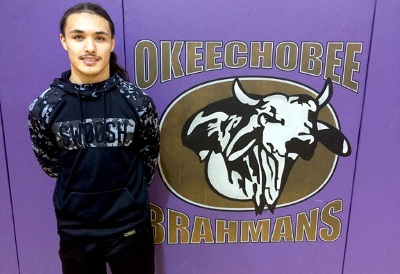 Okeechobee High School wrestler Drayton Billie stands next to the school’s logo March 3, two weeks after he won a district championship in the 138-pound class. 