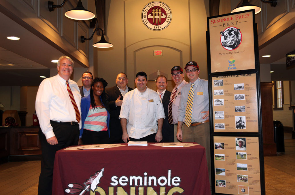 Seminole Pride Beef director of business development Michael Sauceda, thumbs up next to the chef, poses with members of the FSU food service department by the Seminole Pride Beef display in FSU’s Suwannee Room dining hall during the special event that fed 900 people a grand meal of carved striploin steak Oct 14. (Beverly Bidney photo)