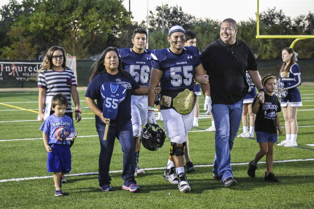 University School senior Brady Latchford (55) is joined by his parents, Amy Latchford and Seminole Police Chief William Latchford, brother and teammate Bradley (56), and other family members during the team’s senior night ceremony Nov. 4 in Davie. (Stephanie Rodriguez photo)