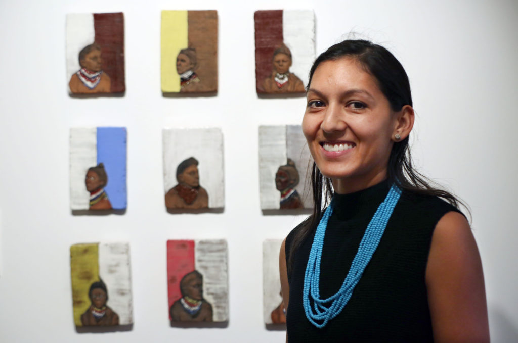 Jessica Osceola stands near some of her bas-relief sculptures at “Thirty-One”, her MFA exhibition at Florida Gulf Coast University’s ArtLab Gallery on Dec. 8. (Beverly Bidney photo)