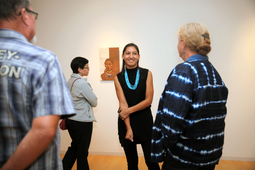 During the closing reception of her MFA Exhibition at FGCU Dec. 8, Jessica Osceola explains some of the processes she used to create her sculptures. (Beverly Bidney photo)