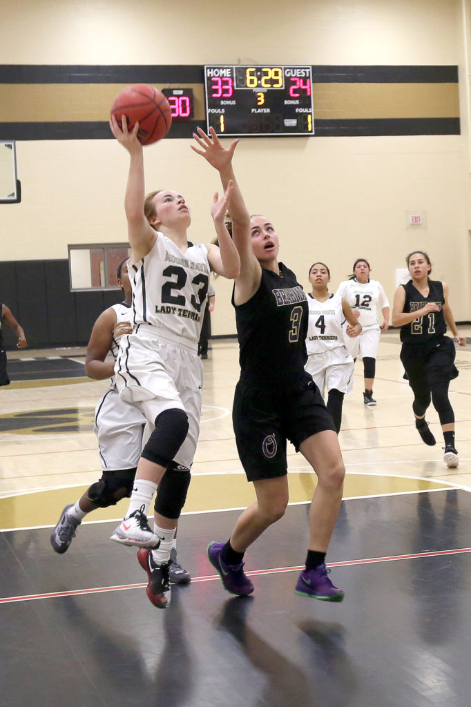 Moore Haven’s Sunni Bearden drives to the hoop while defended by Okeechobee’s Raeley Matthews in a girls high school basketball game Nov. 30. In the background are Moore Haven’s Sydnee Cypress (4) and Aleina Micco (12) and Okeechobee’s Julia Smith (21). (Kevin Johnson photo)