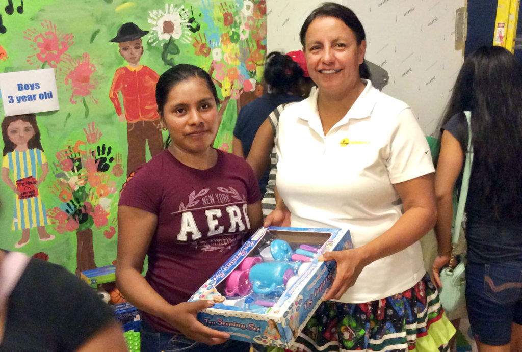 Board Liaison Gale Boone, right, presents a gift to a parent during a gift wrapping program with the Redland Christian Migrant Association on Dec 19 in Immokalee.