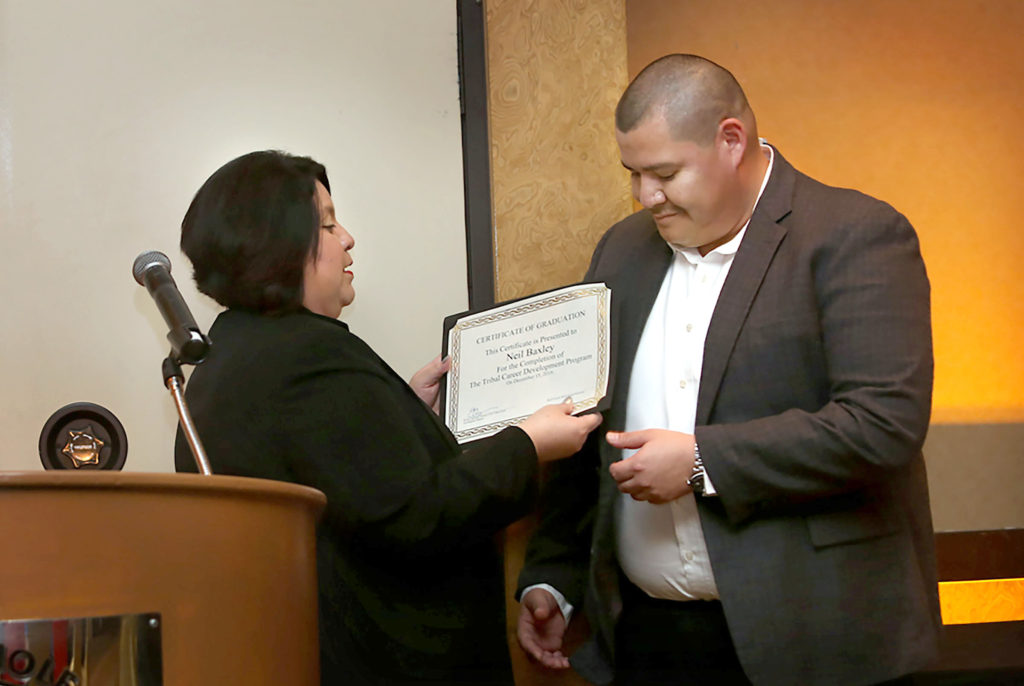 Ervina Capricien, director of Human Resources at Seminole Classic Casino and director of the Tribal Career Development program, presents Neil Baxley with a certificate of graduation from phase 2 of the program that places Tribal citizens in management positions within the Seminole Gaming organization. (Eileen Soler photo)