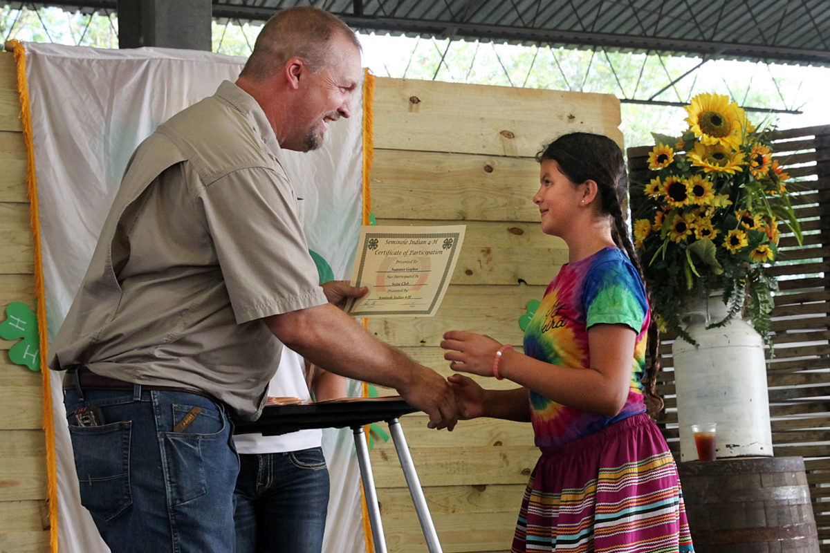 Aaron Stam congratulates Summer Gopher as he presents her with the swine club participation certificate. (Beverly Bidney photo)