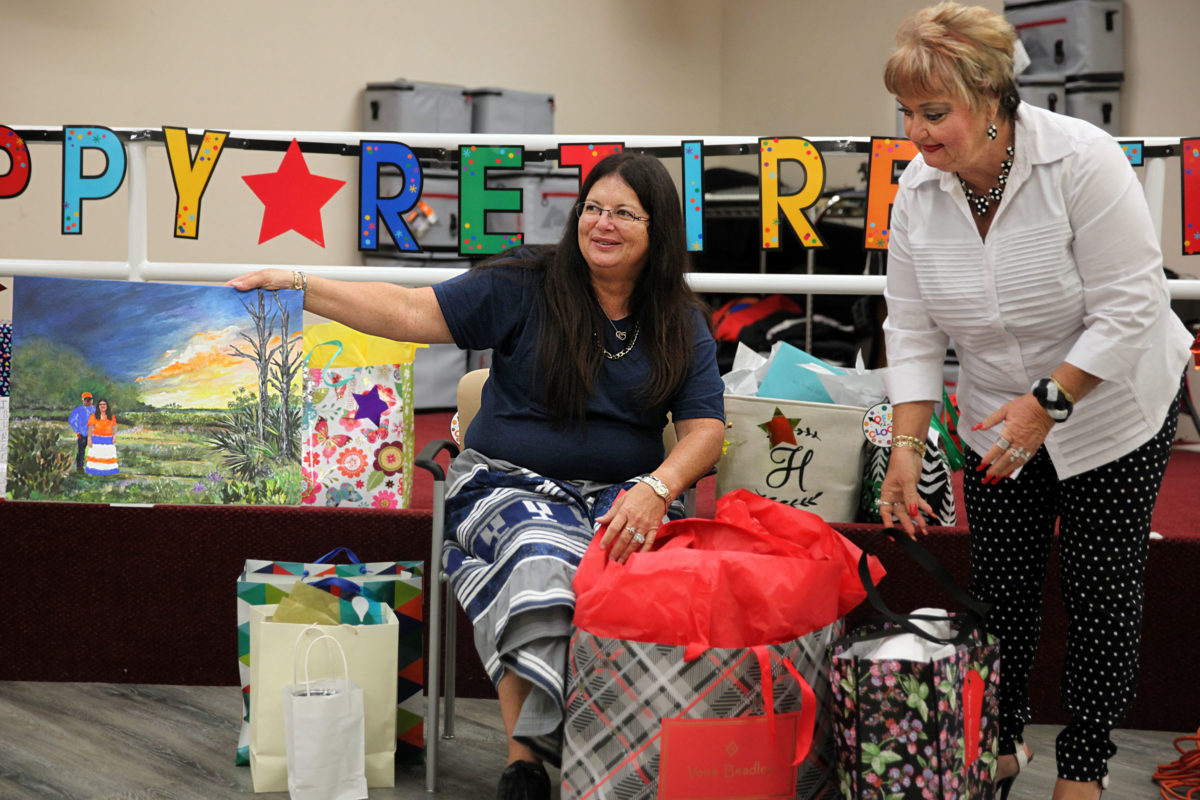 Vickey Huff displays the gift of a painting of herself and her husband John Huff at her retirement party June 22. Newly named Elder Services director Rhonda Goodman assists Huff with the gifts. (Beverly Bidney photo)