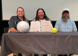 With her parents Mona and Preston next to her, Preslynn Baker holds the paperwork she signed to attend Earlham College, where she’ll play volleyball and softball. A signing ceremony for Baker was held April 25 in the Glades County Auditorium.