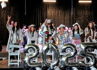 From left to right are Xzavion Tommie, Sarah Robbins, Ian Hernandez-Osceola, Gilbert Guerrero, Aaliyah Billie and Jody Cabral. Students are standing behind large 2025 silver balloons. Some students are moving their tassels to the other side and one student throws their cap.