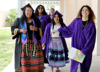 From left to right, Preslynn Baker, Merlelaysia Billie, Willo James, Neela Jones and Lason Baker enjoy their return to PECS. The group smiles and laughs while walking toward the camera in purple and black caps and gowns.