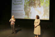 Ashley Stokes, left, and Jill Horwitz speak at the "Good Natured" film screening May 15 at Savor Cinema in Fort Lauderdale. They stand in front of a projector with a photo of Stokes holding a camera on her shoulder. The text to the left of the photo on the projector says "'Good Natured' A Filmmaker's Journey in a Changing Climate. Thank you for attending! Stick around for a panel with the filmmaker and the Climate Resiliency Team."